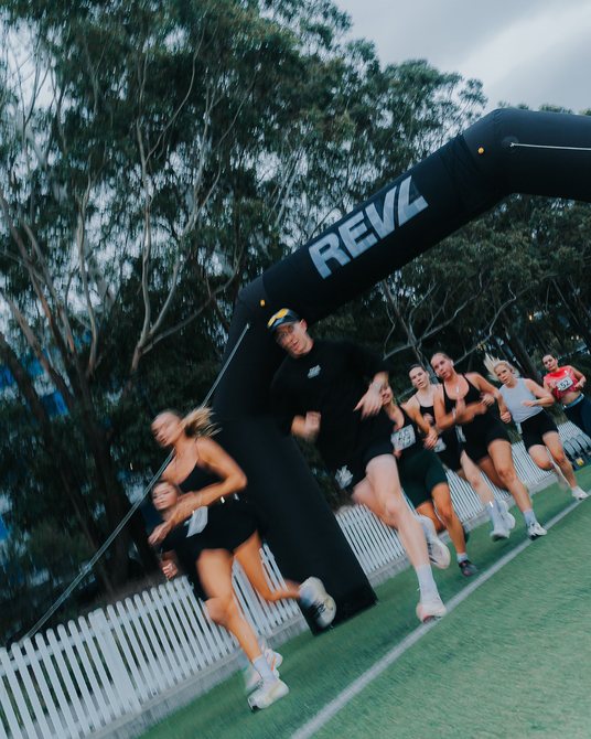 Runners through the REVL arch at a REVL PACE run